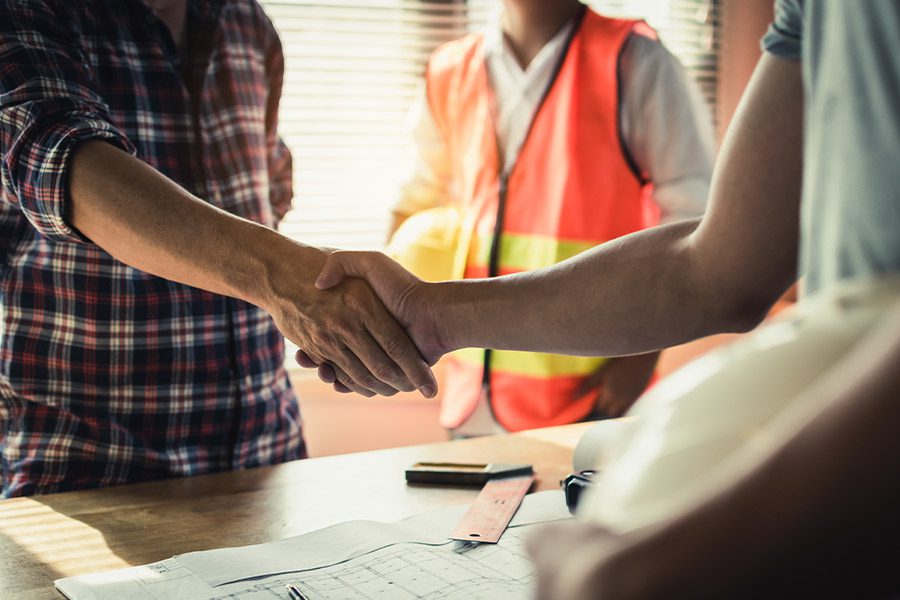 Specialized Business Insurance - Closeup of Contractors and Engineer Shaking Hands in an Office